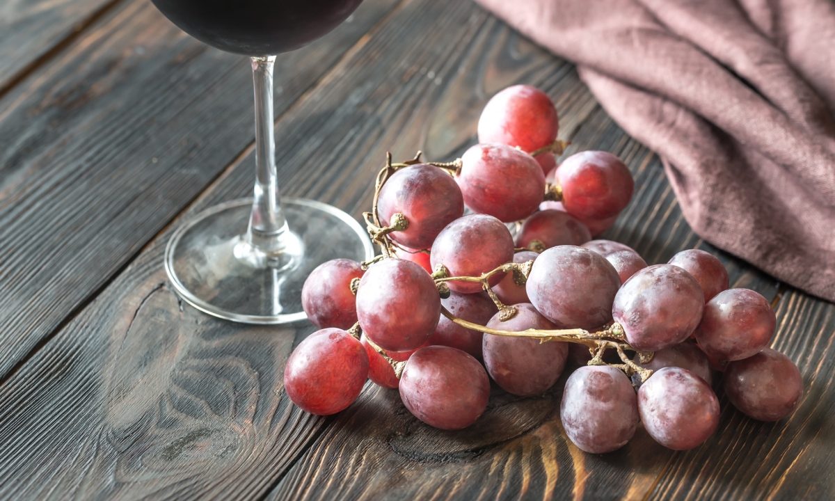 Glass of red wine with bunch of red grape